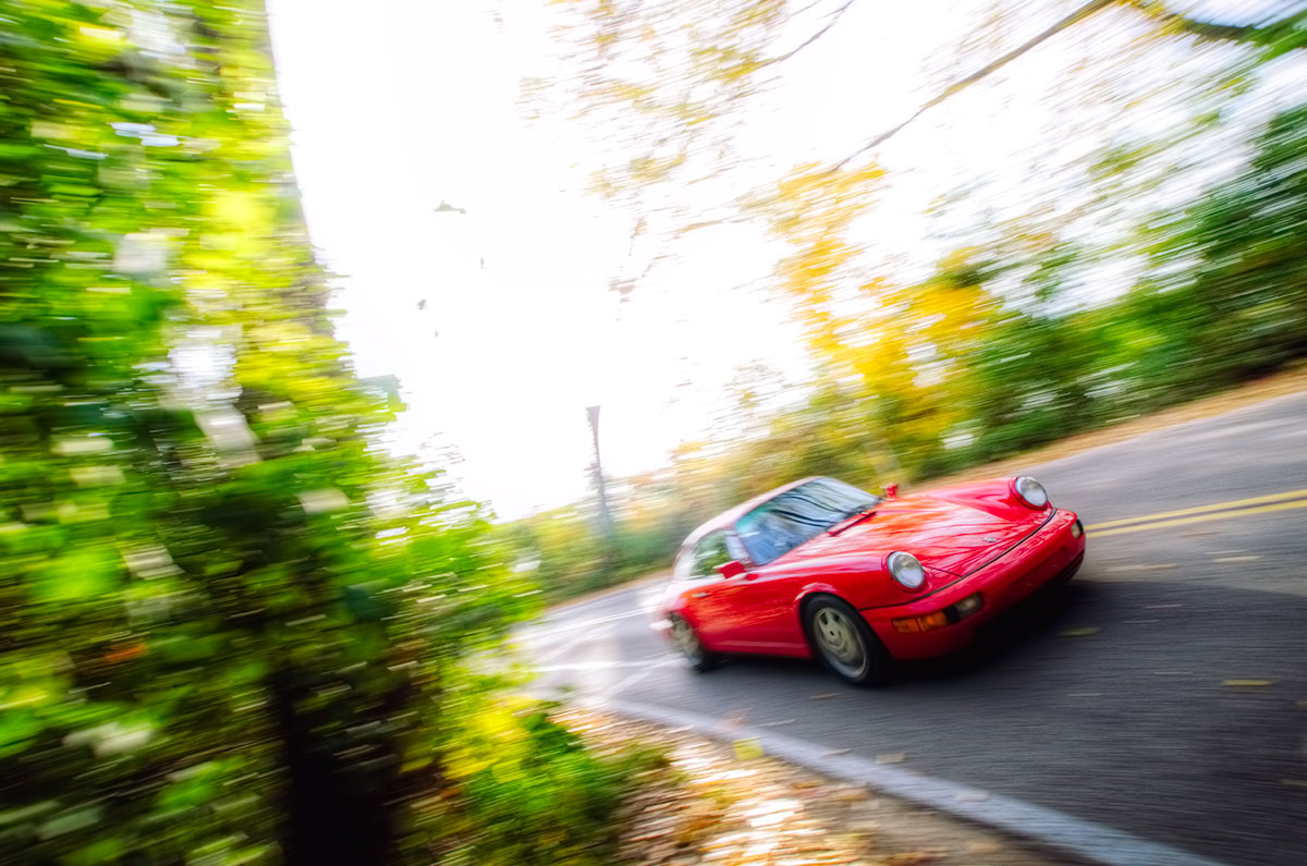 Red Porsche 911 (964) Carrera 4 Emerging from the woods